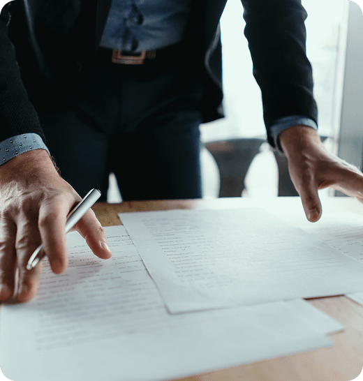 person in suit standing over desk and papers